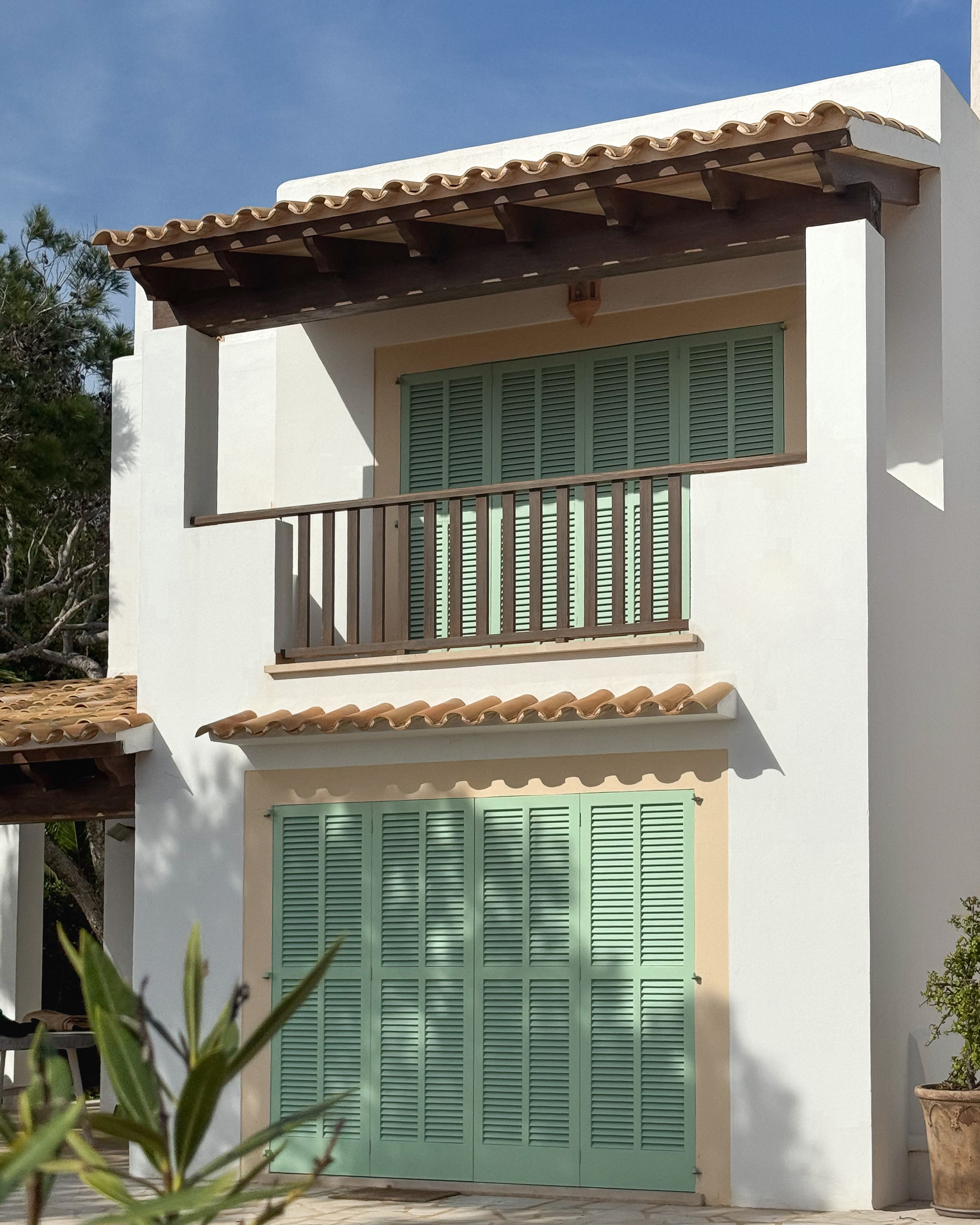 Fachada mediterránea con persianas mallorquinas color verde primavera. 